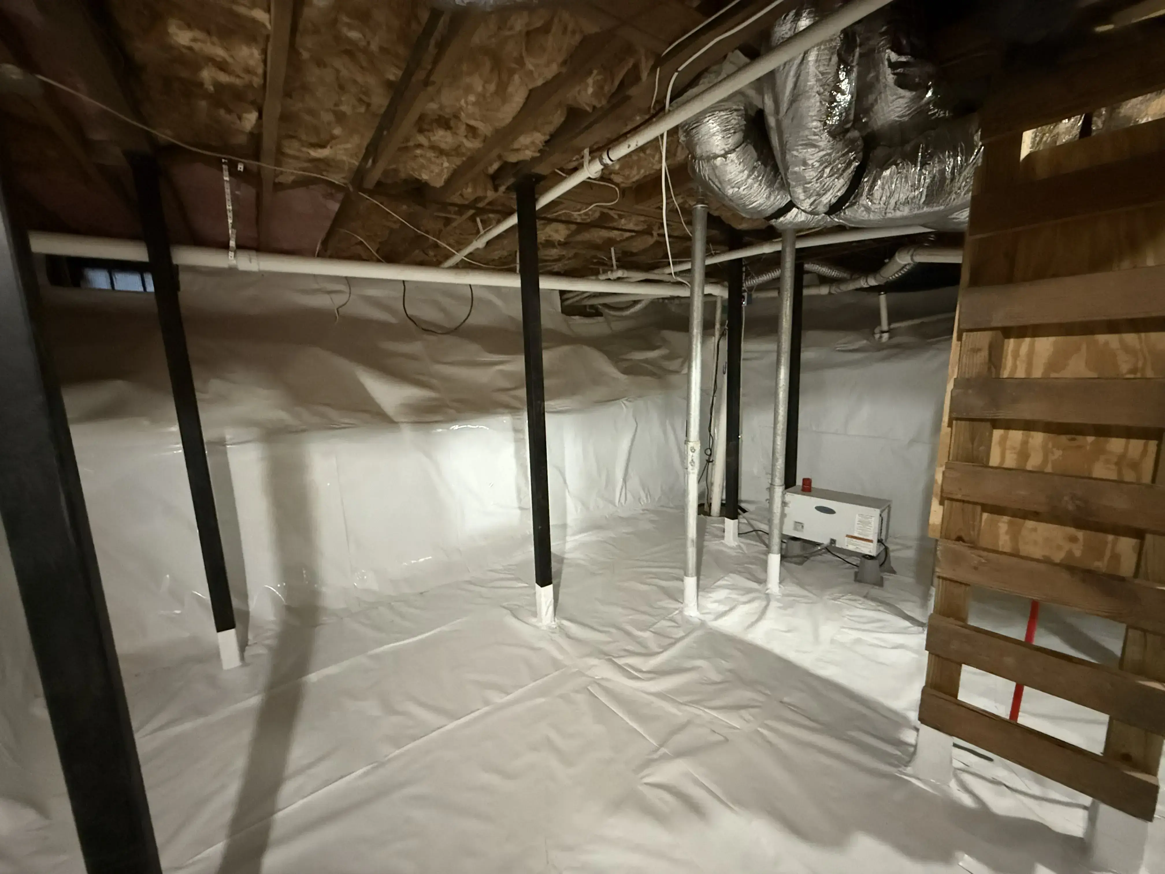 sealed crawlspace with white vapor barrier, insulated ductwork, and dehumidifier system for moisture control and mold prevention